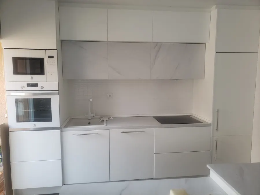 Cocina blanca a medida con columna de horno y frente de mármol en Alicante